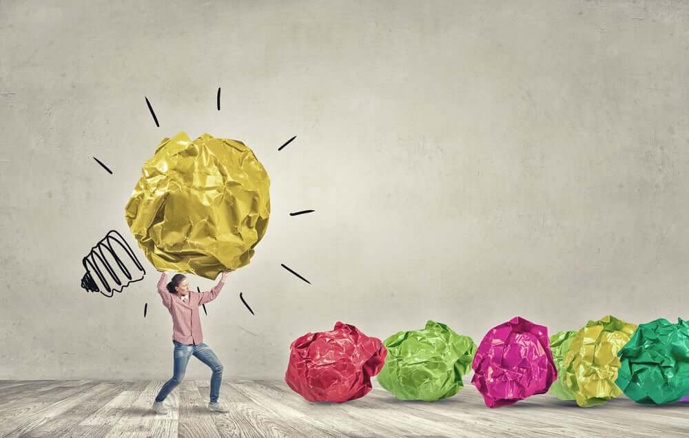 Woman carrying with effort big crumpled ball of paper as creativity sign